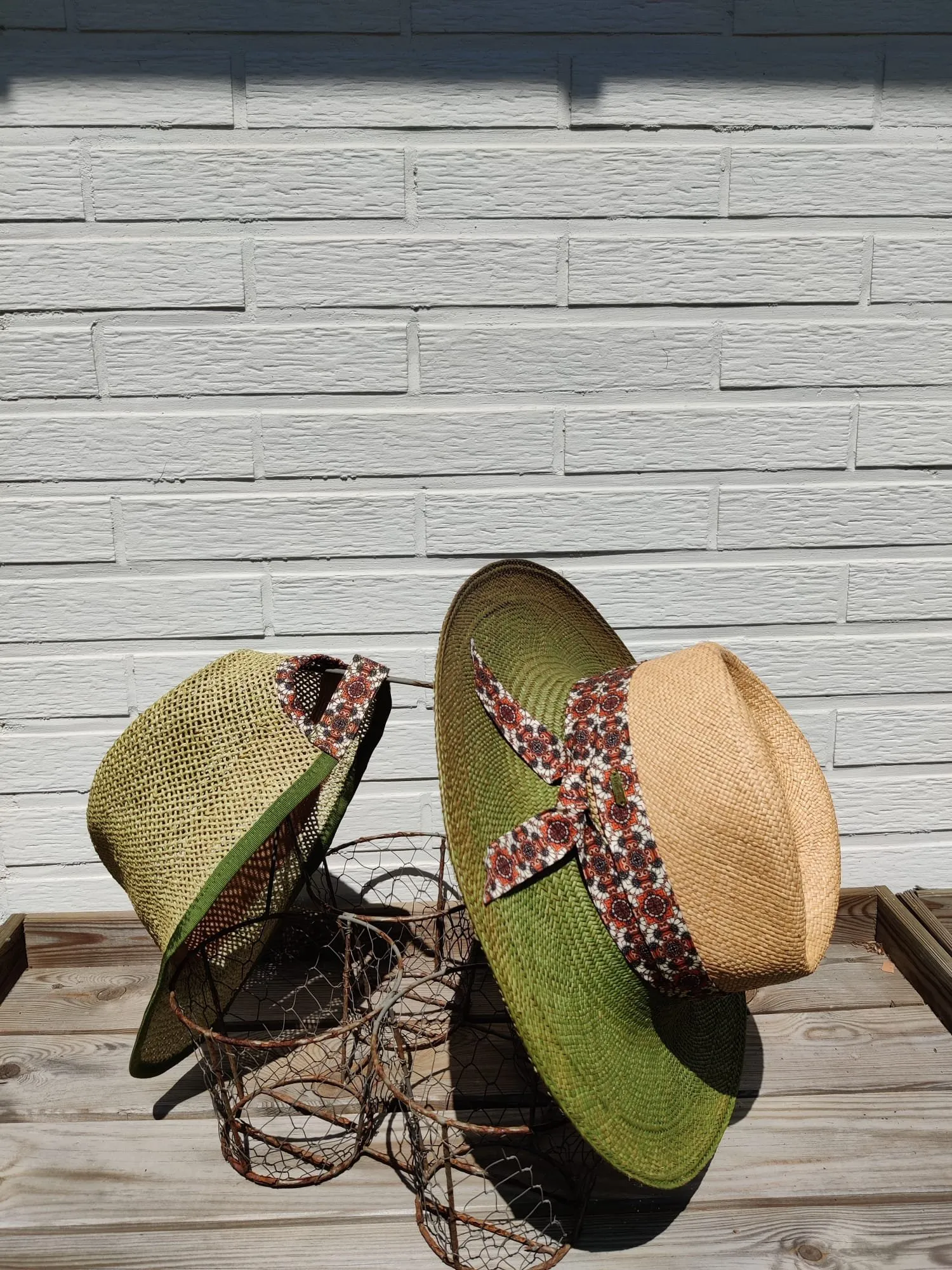 Twee groene strohoeden met een geknoopt lint in retro bloemenprint