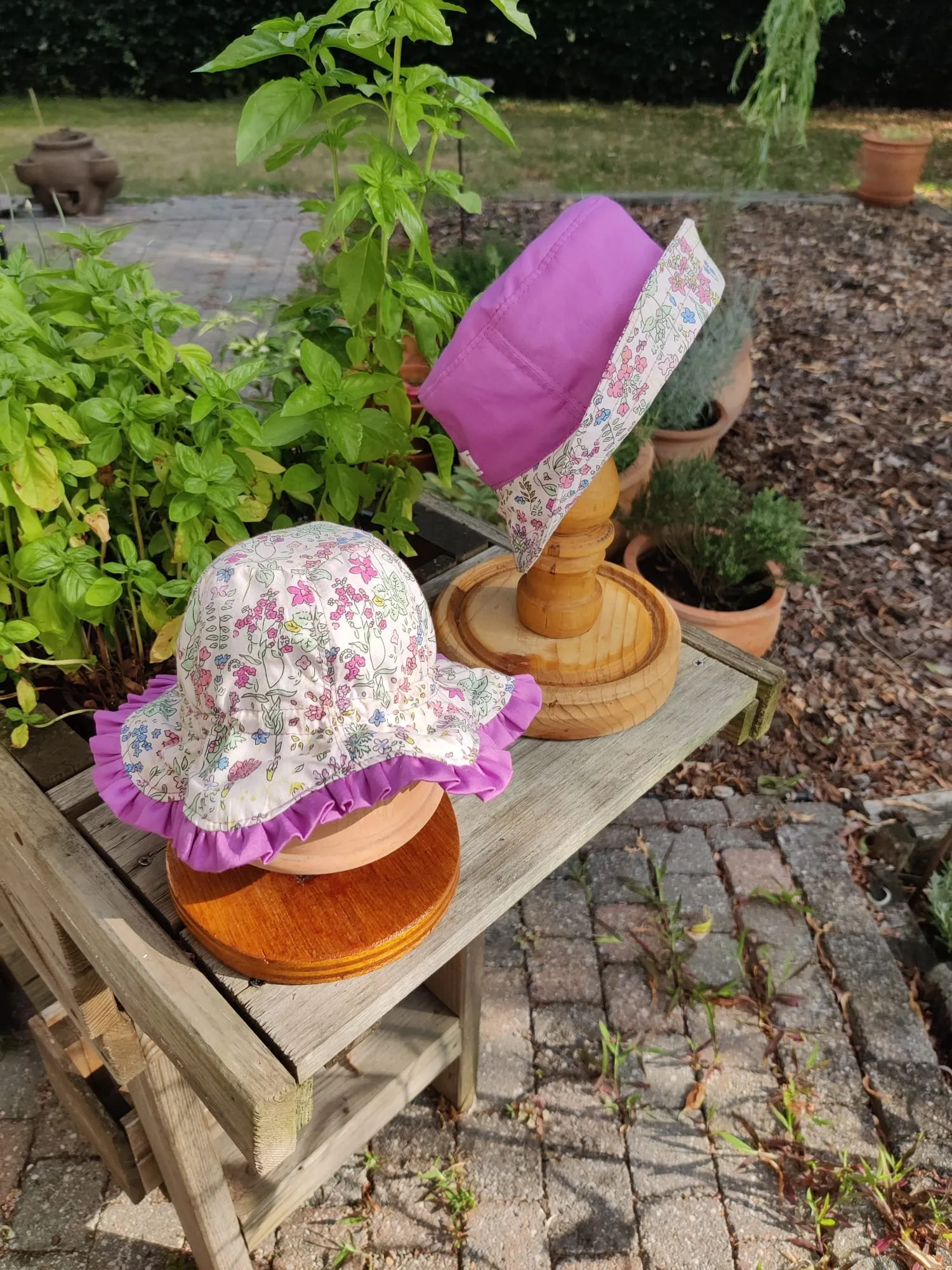 Twee kinderhoedjes in bloemenprint met fuchsia, een met ruche en een gladde buckethoed