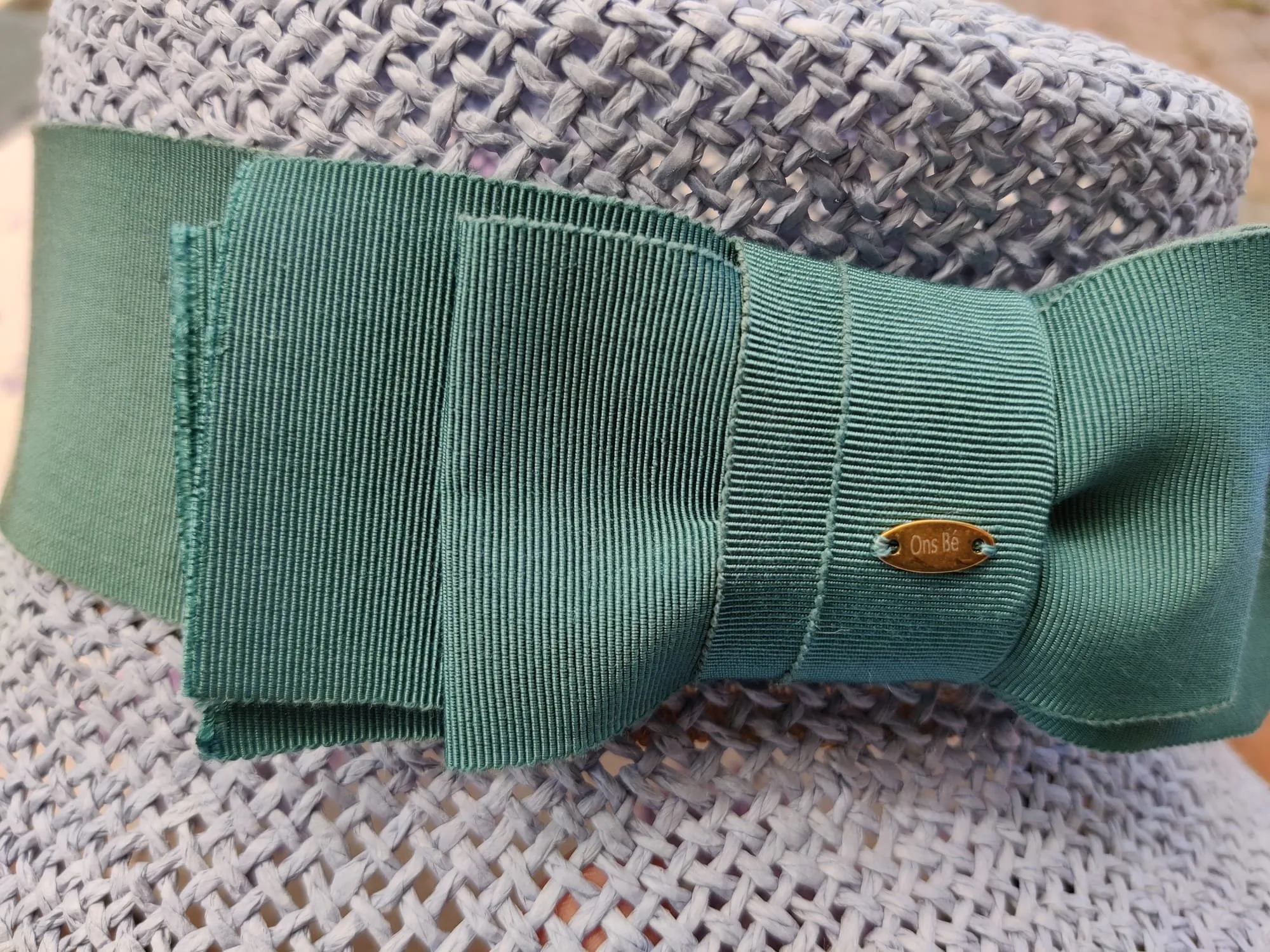 Detail van de strik, met het koperen Ons Bé labeltje